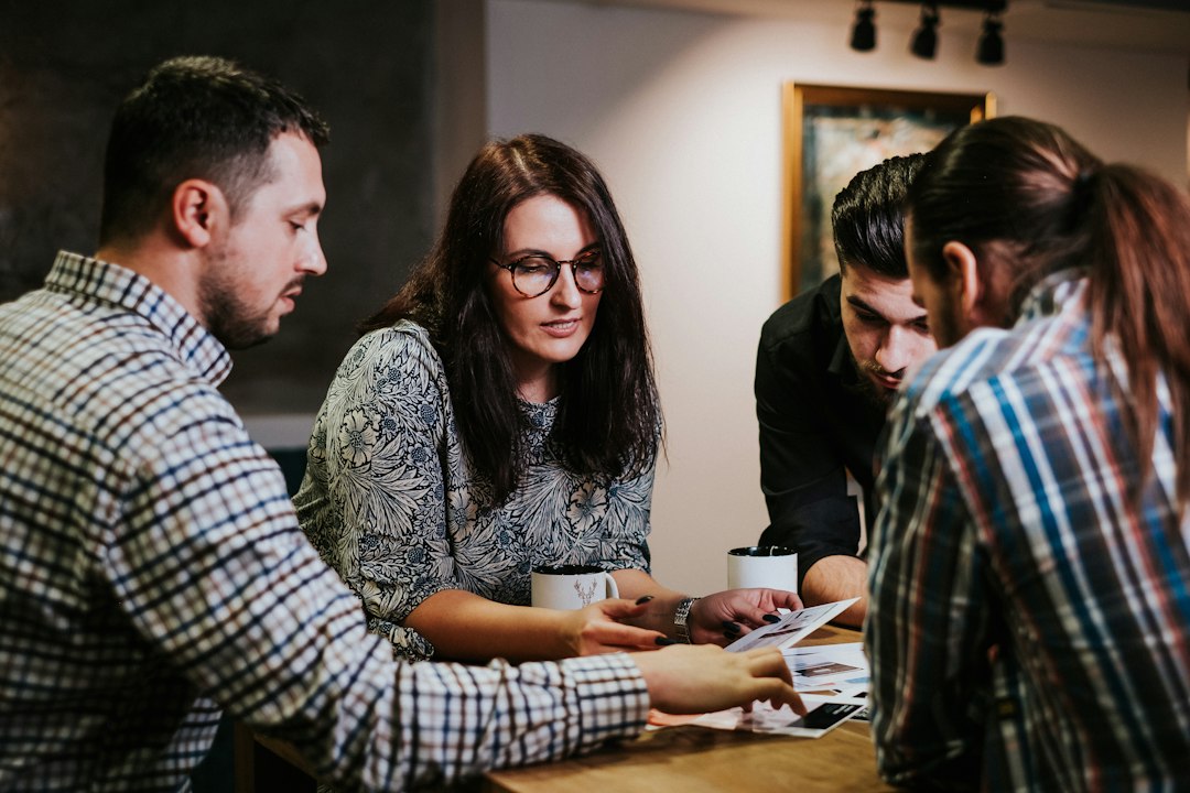 service dog questions — Four people reviewing documents at a wooden table in a workspace